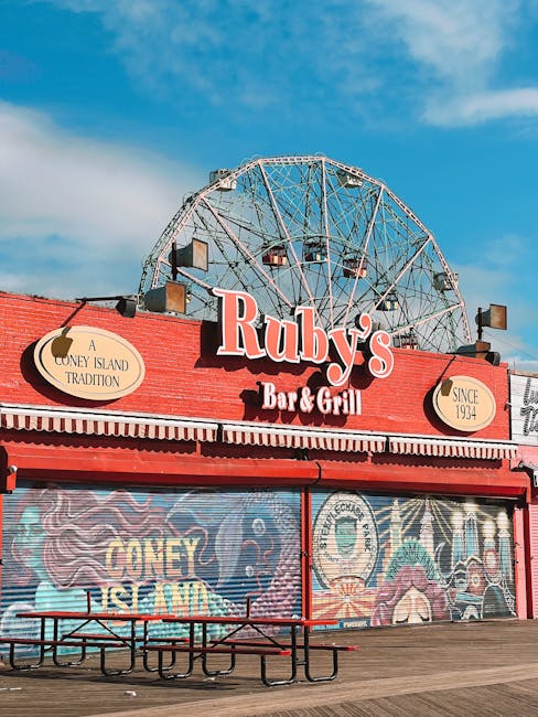 A clear view of a colourful amusement park with a prominent vertical sign reading 'THUNDERBOLT' in red letters on an orange background, part of the ride's structure. Surrounding the ride are various o