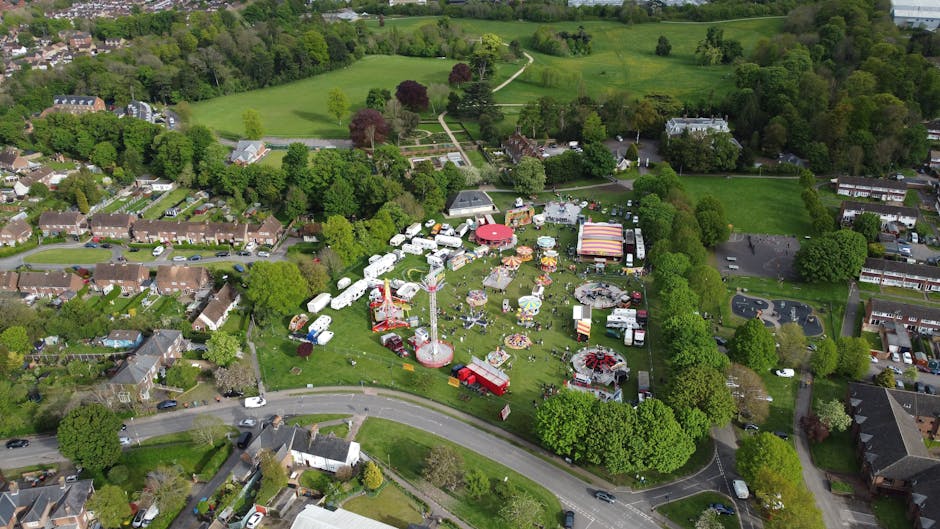 Inside a narrow, elongated wooden corridor with high vaulted ceilings supported by exposed wooden beams, natural light filters through multiple small, decorative leaded glass windows lining both sides of the space. The corridor features wooden panelled walls and a aged wooden floor, with several small wooden chairs placed against the wall on the right side. At the far end, there are cardboard boxes and packing materials indicating a home relocation or packing process. The environment appears to be part of an old building or manor, which is being prepared for moving or furniture transport. This setting reflects a careful and organized preparation stage typical of professional removals by Man with Van Coney Hall, supporting services like packing, loading, and home or office relocation.